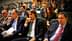 Um grupo de indivíduos sentados em uma sala de conferência, alguns usando fones de ouvido e envolvidos em uma discussão. Olive Oil Times