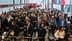 Large crowd of people waiting in line at an event entrance with ticket barriers. - Olive Oil Times