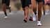 Close-up of a runner's foot in athletic shoes on a road with other runners in the background. - Olive Oil Times