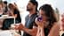 Two participants in a tasting session, one smelling from a blue container while the other is seated with eyes closed. - Olive Oil Times