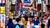 Une foule de personnes se promenant dans un marché de rue animé rempli de panneaux colorés au Japon. - Olive Oil Times