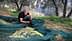 Uomo che raccoglie le olive da una rete in un uliveto circondato da alberi. - Olive Oil Times
