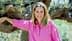 Woman with long hair wearing a pink shirt, leaning against an olive tree with a smile. - Olive Oil Times