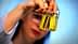 Persona che tiene in mano due piccole bottiglie di vetro contenenti olio d'oliva con liquido giallo all'interno. Olive Oil Times