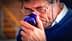 Man with glasses holding a blue glass cup to his nose, appearing to smell it. - Olive Oil Times