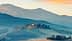 A scenic view of a Tuscan landscape featuring rolling hills and a farmhouse on a hilltop. - Olive Oil Times