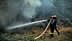 Firefighters using a hose to extinguish flames in a forested area during a wildfire. - Olive Oil Times