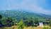 Une zone montagneuse couverte de végétation verte et de formations rocheuses sous un ciel bleu avec des nuages. - Olive Oil Times