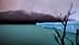 A glacier with a blue ice edge in a body of water, surrounded by mountains and a cloudy sky. - Olive Oil Times