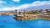 Coastal view featuring a city skyline with mountains in the background and clear blue water. - Olive Oil Times