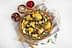 A vibrant salad featuring roasted cauliflower, arugula, nuts, and pomegranate seeds on a wooden plate. - Olive Oil Times