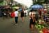 Des gens font leurs courses sur un marché de rue avec divers légumes exposés sur le sol. Olive Oil Times