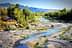Un río que serpentea a través de un paisaje con árboles y zonas rocosas bajo un cielo despejado. Olive Oil Times
