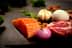 Raw salmon fillet, meat, onion, garlic, egg, and almonds arranged on a dark surface. - Olive Oil Times