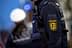 Close-up of a police officer's uniform featuring a badge and radio equipment. - Olive Oil Times