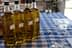 Four bottles of olive oil arranged on a checkered tablecloth with glasses nearby. - Olive Oil Times