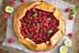 Eine Himbeer-Galette mit frischen Minzblättern und Limettenscheiben auf einem Backblech. - Olive Oil Times