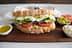 Ein Sandwich aus Vollkornbrot, gefüllt mit Eiersalat, Gurken, Tomaten und Essiggurken. - Olive Oil Times