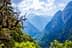 Eine malerische Aussicht auf ein Bergtal mit Bäumen und felsigen Gipfeln unter einem bewölkten Himmel. - Olive Oil Times