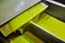 Green olive oil flowing from a metal spout during the extraction process. - Olive Oil Times