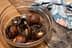 A glass bowl containing soaked mushrooms in liquid, placed on a wooden surface. - Olive Oil Times