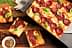 Üzerine domates sosu ve taze fesleğen yaprakları dökülerek fırın tepsisinde servis edilen dikdörtgen pepperoni pizza. Olive Oil Times