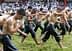 Young men in wet clothing walking in a line during a traditional event on a grassy field. - Olive Oil Times