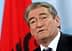 Man speaking at a podium with an Albanian flag in the background. - Olive Oil Times