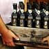 A wooden crate filled with bottles of Willow Creek olive oil held by two people. - Olive Oil Times