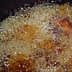 Bubbling oil in a pot during the deep frying process with food submerged. - Olive Oil Times
