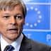 Dacian Ciolos speaking during a press conference in front of a blue backdrop with the European Union flag. - Olive Oil Times