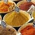 Bowls filled with various spices, each labeled with a small black sign for identification. - Olive Oil Times