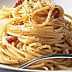 A serving of spaghetti topped with bacon pieces and grated cheese on a white plate. - Olive Oil Times