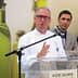 A chef in a white coat speaking at a podium with a microphone during an event. - Olive Oil Times