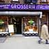 Storefront of Grosseria Italiana with a sign and display of flowers and produce. - Olive Oil Times