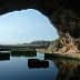 View of a cave opening with water reflecting the surrounding rock formations. - Olive Oil Times