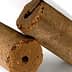 Two cylindrical olive oil briquettes with a textured surface and a hole in the center. - Olive Oil Times