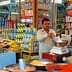 A shop displaying a variety of spices and packaged goods with a man measuring ingredients. - Olive Oil Times