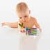 Infant exploring a colorful toy with numbers and letters while holding a small plant. - Olive Oil Times