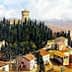 Aerial view of Castello del Trebbio surrounded by trees and buildings in a hilly landscape. - Olive Oil Times