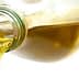 A glass bottle pouring olive oil with a clear stream of liquid flowing from the spout. - Olive Oil Times