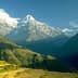 Snow-capped mountains in Nepal with clear blue sky and green hills in the foreground. - Olive Oil Times