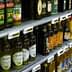 Multiple bottles of olive oil displayed on shelves in a grocery store. - Olive Oil Times