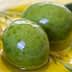 Three green olives resting in a pool of olive oil with leaves nearby. - Olive Oil Times