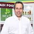 Man in a white shirt standing in front of Wadi Food branding and product display. - Olive Oil Times
