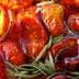 Close-up of oven dried tomatoes submerged in olive oil with rosemary sprigs. - Olive Oil Times