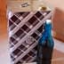 A square metal container with a patterned design next to a blue glass bottle. - Olive Oil Times