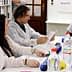 A group of individuals in lab coats engaged in a discussion around a table with various items and documents. - Olive Oil Times