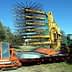 Olive harvesting machine with a large rake attachment and a tractor in a field. - Olive Oil Times