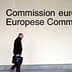 A person walking past the European Commission signage with the EU flag displayed on the wall. - Olive Oil Times